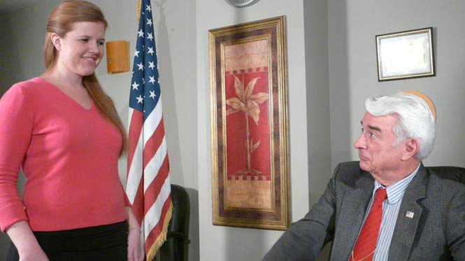 young woman and older man in an office with American flag
