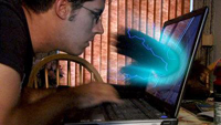 Electrified blue hand coming out of laptop screen into man's face